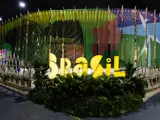 A Brazil-themed exhibition booth at COP29, featuring large illuminated text reading "Brasil," surrounded by greenery and colourful banners, with a sign saying "See you at COP30!"